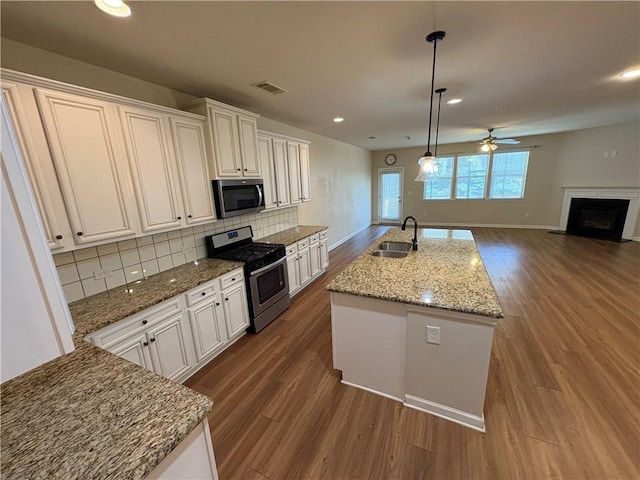 kitchen with dark wood-style flooring, backsplash, appliances with stainless steel finishes, and a sink