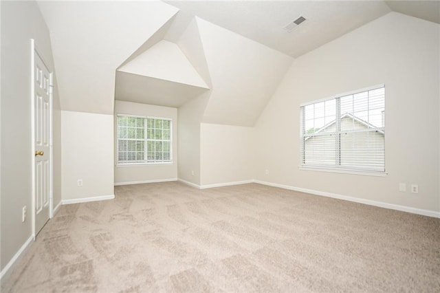 bonus room featuring a wealth of natural light, lofted ceiling, and light carpet