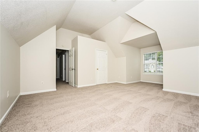 additional living space featuring lofted ceiling, light carpet, and a textured ceiling