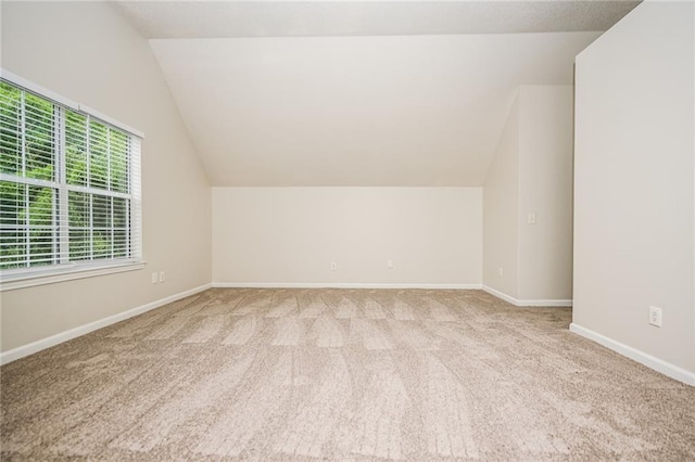 additional living space featuring vaulted ceiling and light carpet