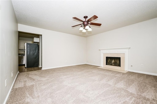 unfurnished living room with ceiling fan, a fireplace, and carpet