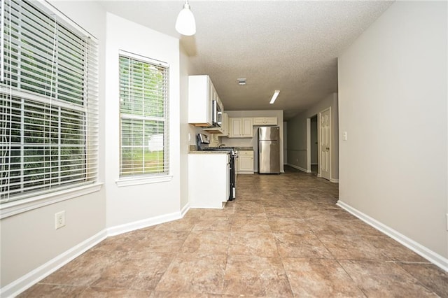 kitchen featuring white cabinets, decorative light fixtures, a textured ceiling, and appliances with stainless steel finishes