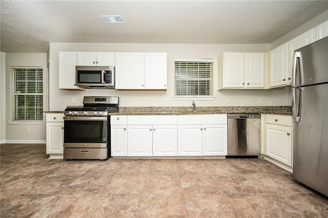 kitchen with appliances with stainless steel finishes, sink, and white cabinets