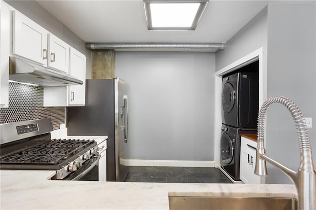 115 W Peachtree Pl NW Unit 602, Atlanta, GA 30313 - kitchen with under cabinet range hood, stainless steel range with gas stovetop, stacked washer and clothes dryer, baseboards, and white cabinets
