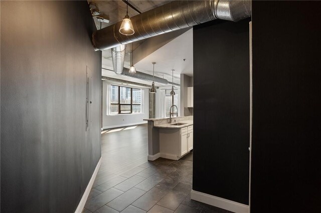 115 W Peachtree Pl NW Unit 602, Atlanta, GA 30313 - kitchen featuring a sink, baseboards, white cabinets, decorative light fixtures, and a peninsula