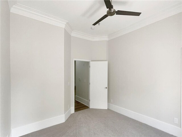 carpeted spare room featuring ceiling fan and crown molding