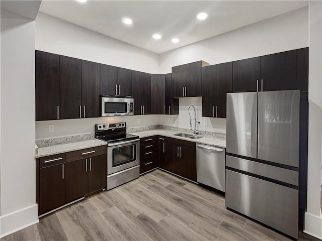 kitchen with sink, appliances with stainless steel finishes, light hardwood / wood-style floors, and dark brown cabinets