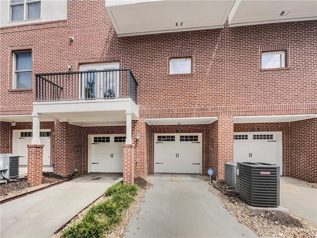 view of front of property featuring a balcony, central AC unit, and a garage