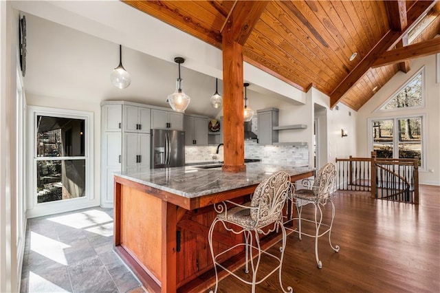 kitchen featuring tasteful backsplash, stainless steel fridge, a breakfast bar area, and stone counters