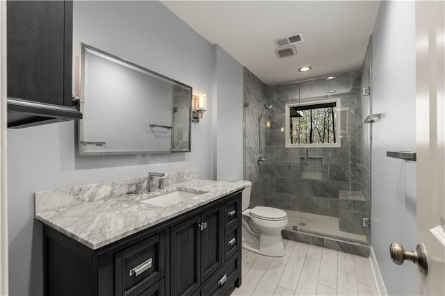 bathroom featuring a shower with door, vanity, wood-type flooring, and toilet