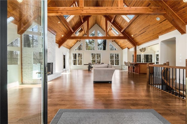 living room with high vaulted ceiling, a fireplace, a skylight, wood-type flooring, and wooden ceiling