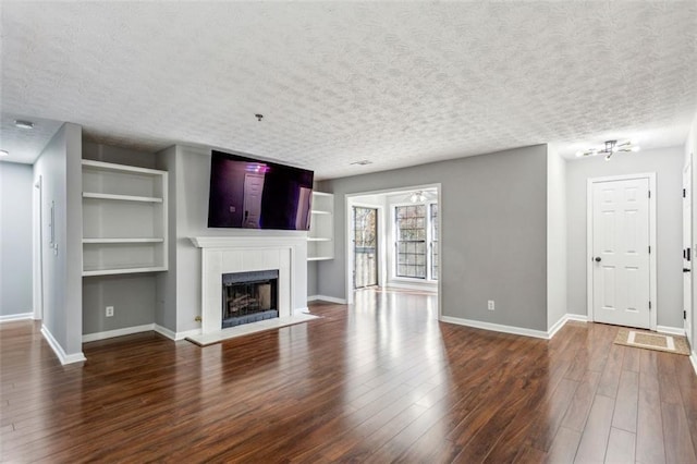 unfurnished living room featuring a fireplace, a textured ceiling, and dark wood-type flooring