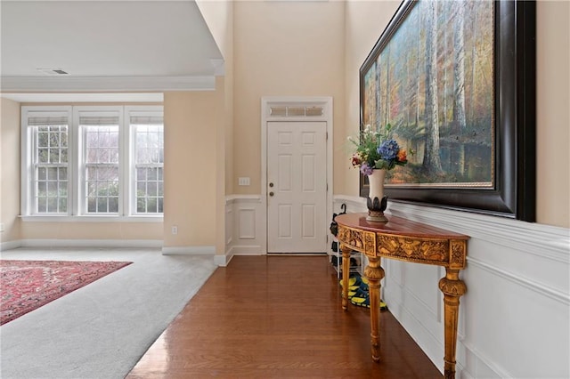 foyer featuring dark colored carpet and ornamental molding