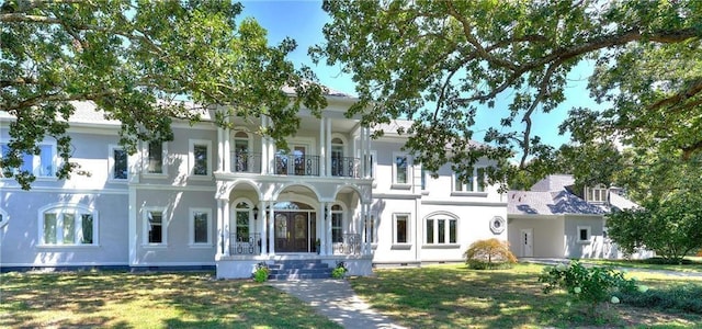 view of front of home with a balcony, stucco siding, and a front yard