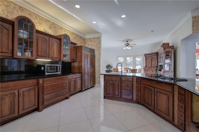 kitchen with a kitchen island with sink, sink, crown molding, stainless steel appliances, and decorative columns