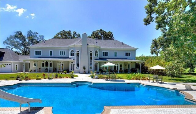 view of pool with a yard, a diving board, a patio area, and a water slide