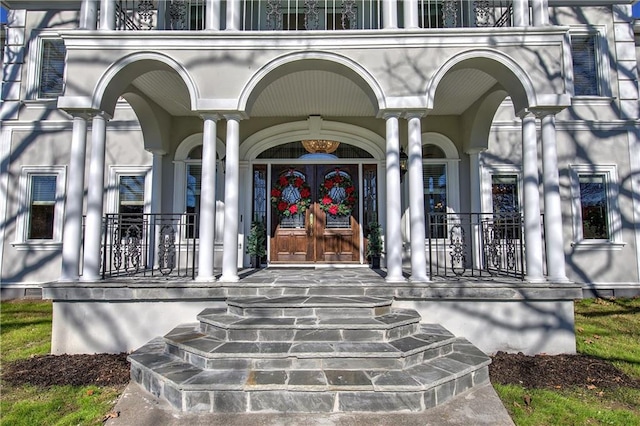 property entrance with covered porch and french doors