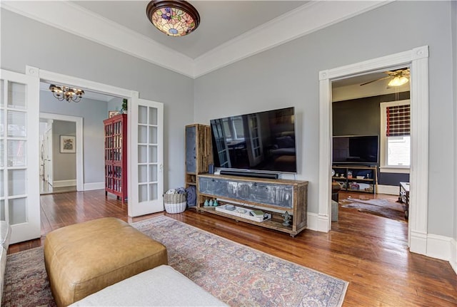 living room featuring a chandelier, baseboards, french doors, wood-type flooring, and crown molding