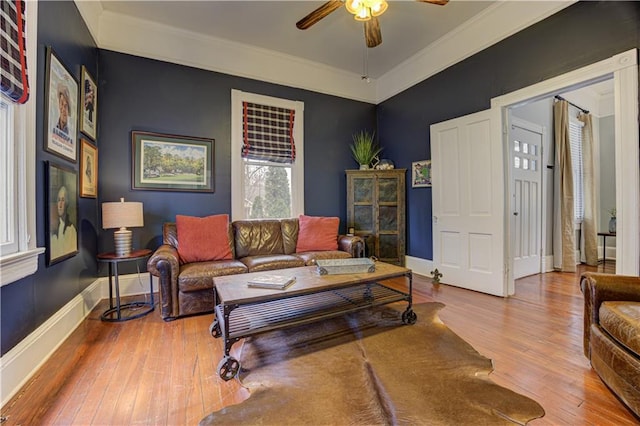 living room featuring crown molding, ceiling fan, hardwood / wood-style flooring, and baseboards