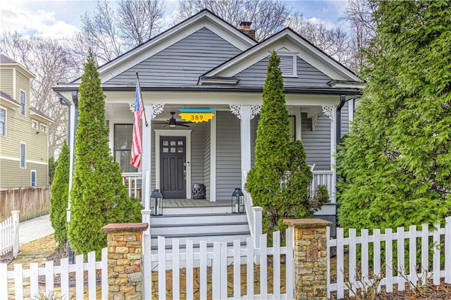 view of front facade with a porch, a chimney, and a fenced front yard