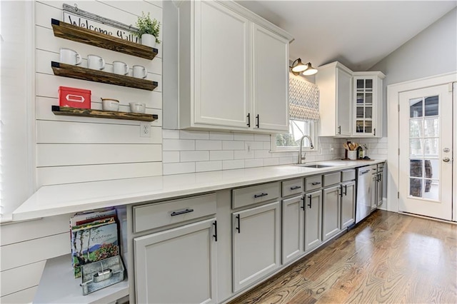 kitchen featuring tasteful backsplash, wood finished floors, gray cabinets, open shelves, and stainless steel dishwasher