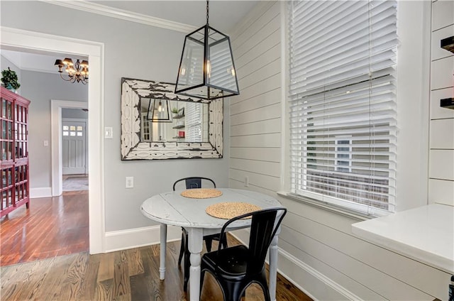 dining space featuring a chandelier, wood walls, wood finished floors, baseboards, and crown molding