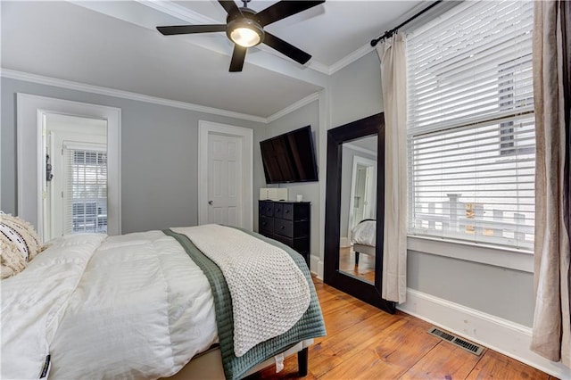 bedroom featuring light wood finished floors, visible vents, multiple windows, and ornamental molding