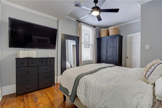 bedroom with ceiling fan, baseboards, wood finished floors, and crown molding