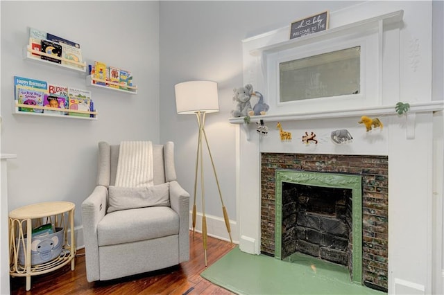 sitting room featuring a fireplace, wood finished floors, and baseboards