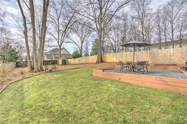 view of yard featuring a fenced backyard, a storage unit, and an outbuilding