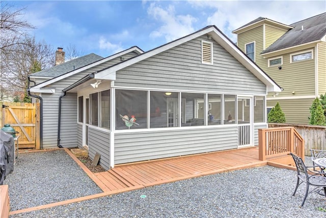 rear view of property with fence, a sunroom, a wooden deck, a gate, and a chimney