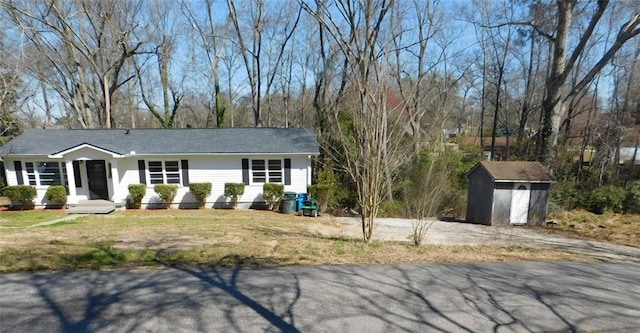 single story home with a storage unit, a front lawn, and an outdoor structure