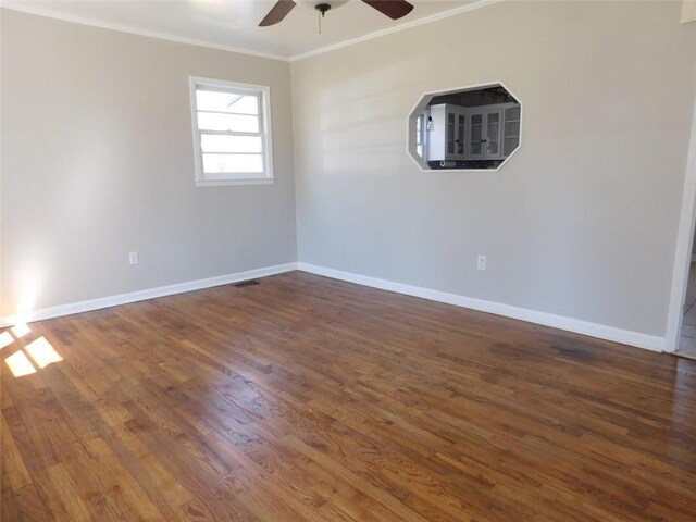 empty room featuring ornamental molding, plenty of natural light, dark wood finished floors, and visible vents