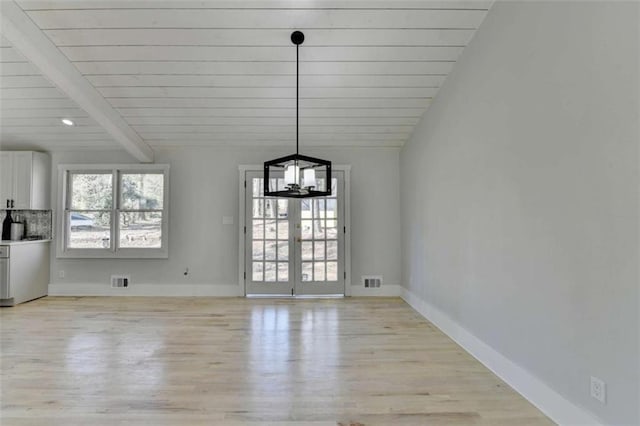 unfurnished dining area with an inviting chandelier, lofted ceiling with beams, and light wood-type flooring