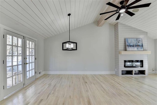 unfurnished living room with light hardwood / wood-style flooring, a large fireplace, vaulted ceiling with beams, and french doors