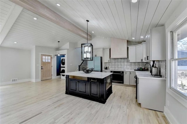 kitchen featuring stainless steel fridge, white cabinets, decorative backsplash, hanging light fixtures, and a center island