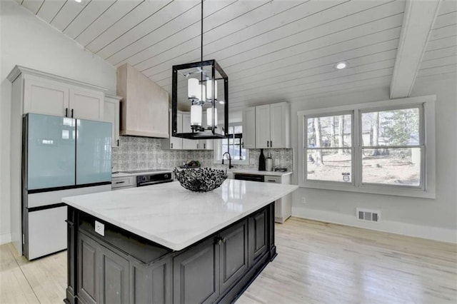 kitchen with white refrigerator, a center island, pendant lighting, and decorative backsplash