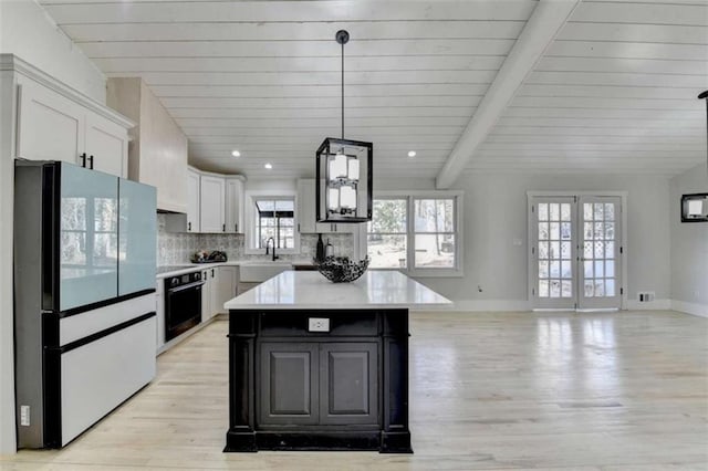 kitchen with white cabinetry, sink, oven, white refrigerator, and a center island