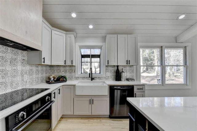 kitchen with white cabinetry, black dishwasher, sink, decorative backsplash, and wall oven