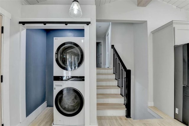 laundry room with stacked washer / drying machine and light hardwood / wood-style floors