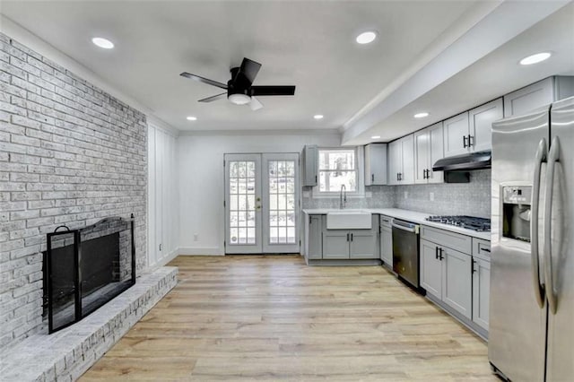 kitchen with sink, gray cabinetry, light hardwood / wood-style flooring, stainless steel appliances, and decorative backsplash