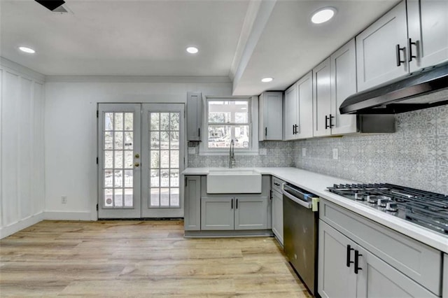 kitchen featuring sink, light hardwood / wood-style flooring, gray cabinetry, stainless steel appliances, and tasteful backsplash