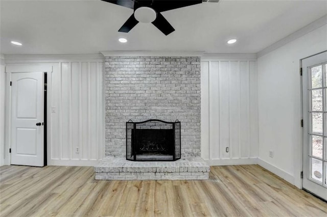 unfurnished living room with ornamental molding, a brick fireplace, ceiling fan, and light hardwood / wood-style flooring