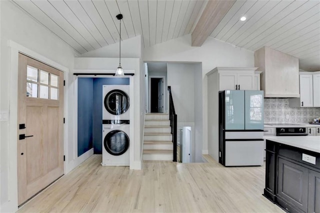 kitchen with stacked washing maching and dryer, white cabinetry, lofted ceiling with beams, decorative light fixtures, and white fridge