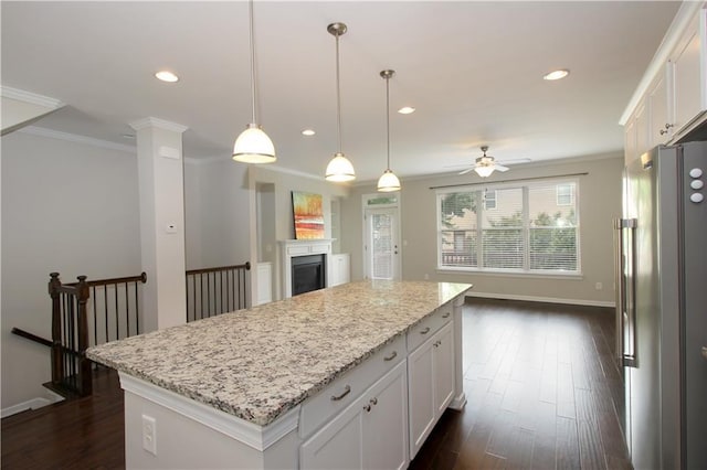 kitchen featuring freestanding refrigerator, ornamental molding, a ceiling fan, a center island, and white cabinetry