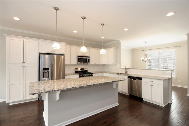 kitchen featuring appliances with stainless steel finishes, a peninsula, a sink, crown molding, and white cabinets