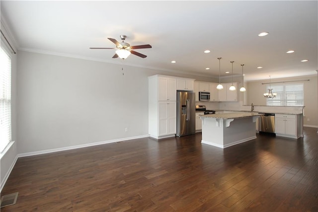 kitchen featuring appliances with stainless steel finishes, a breakfast bar area, white cabinets, ornamental molding, and a ceiling fan
