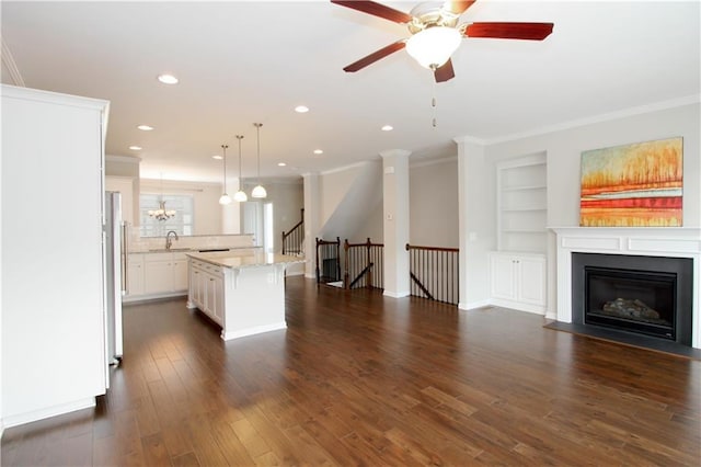 kitchen with a sink, ornamental molding, a breakfast bar area, built in shelves, and open floor plan