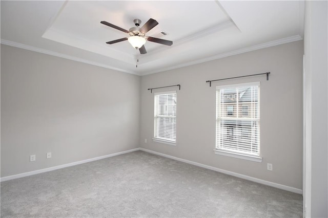 empty room featuring a tray ceiling, ornamental molding, carpet floors, ceiling fan, and baseboards