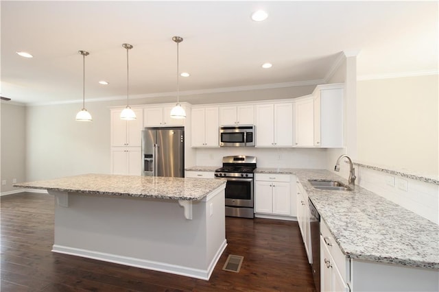 kitchen featuring stainless steel appliances, a sink, ornamental molding, a breakfast bar area, and white cabinets